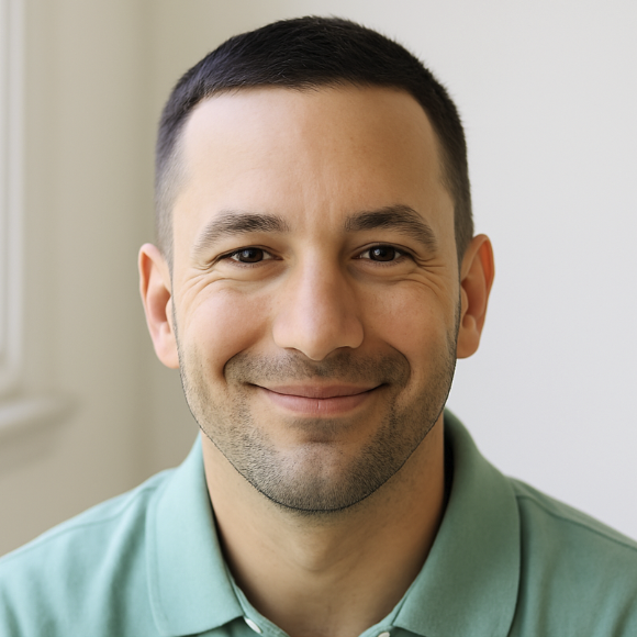 Smiling man with short dark hair wearing a light green collared shirt sitting in a bright room for testimonial section on the website